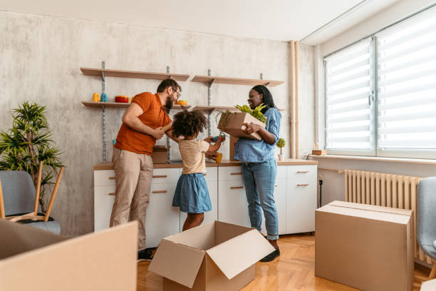A woman with her husband and their child unpacking in their new apartment. Carrying boxes.